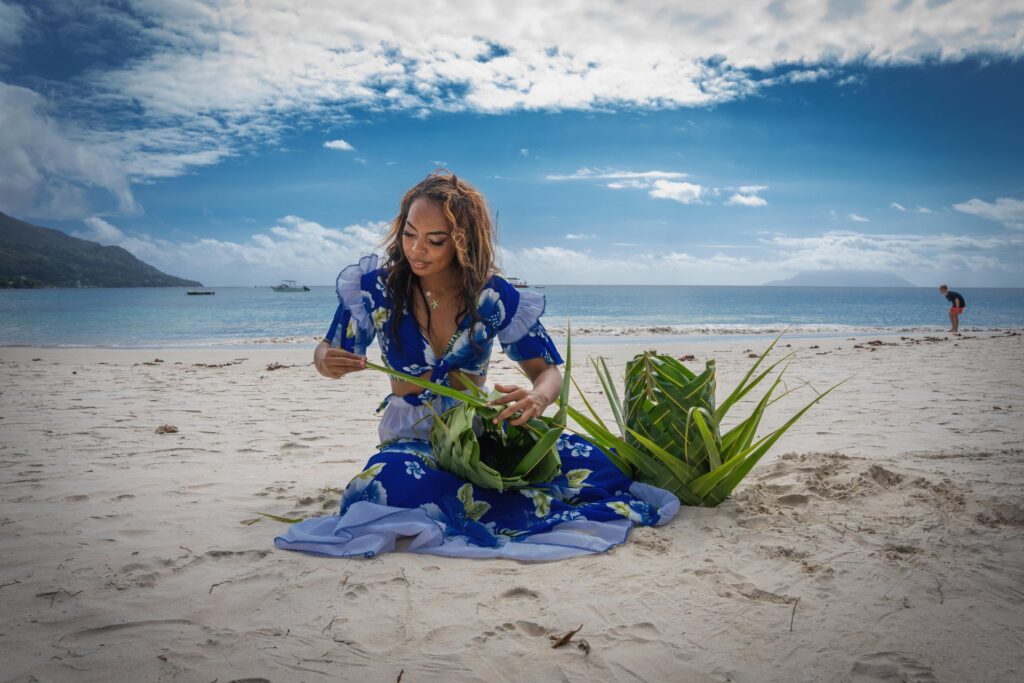 A woman weaving palm leaves on a Seychelles beach