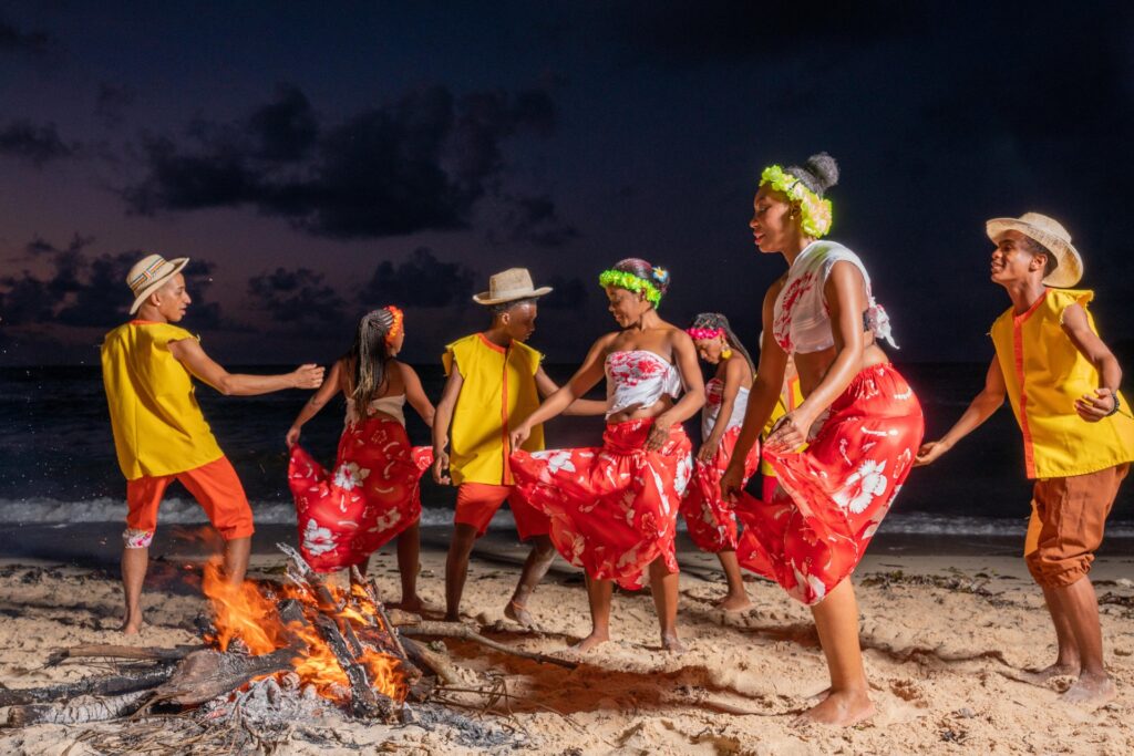 Seychellois dancers in colourful Creole clothing beside a beach bonfire